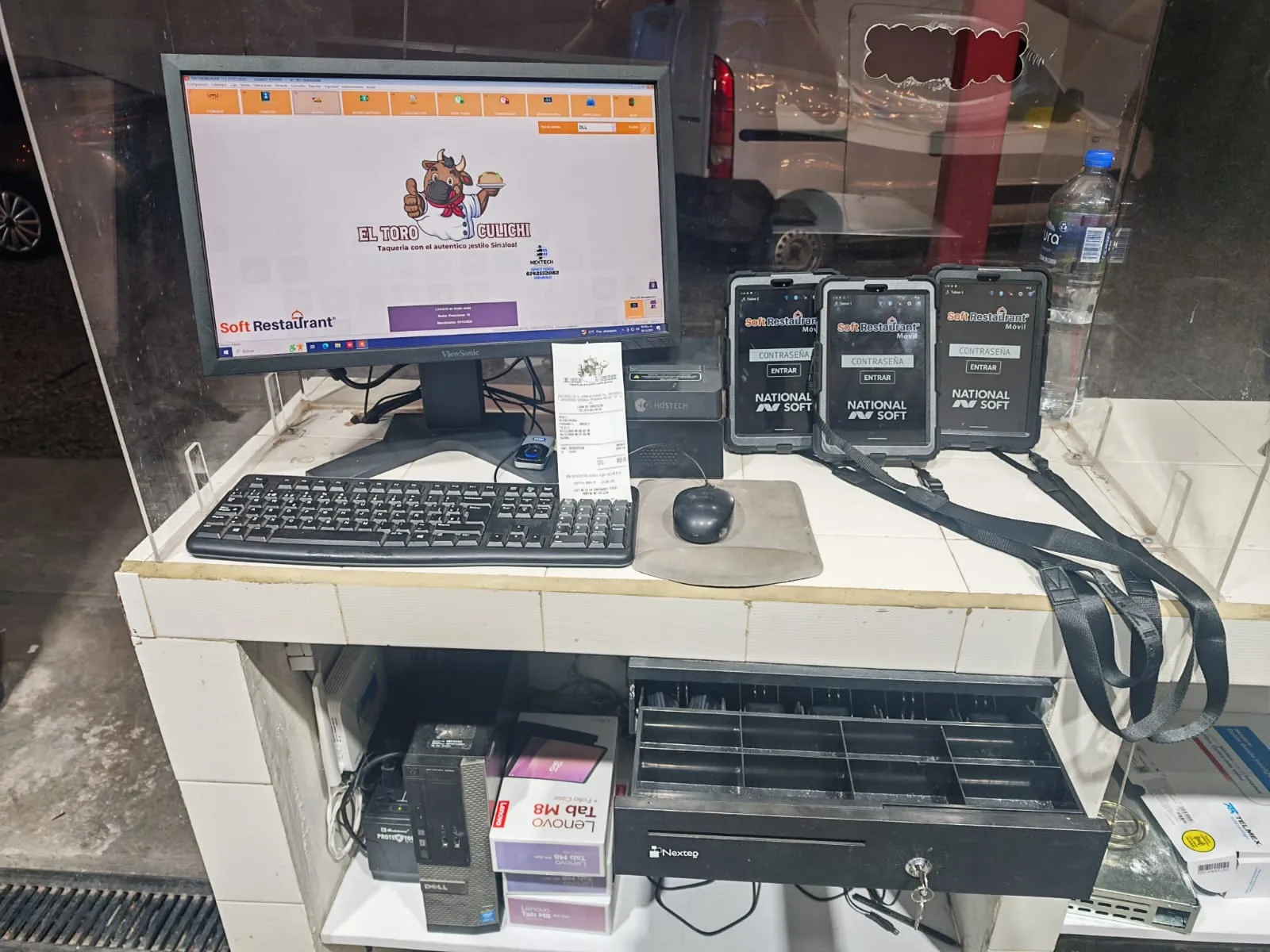 Punto de venta con comanderos y cajón de dinero en una hamburguesería
